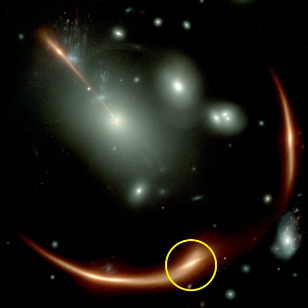 Immagine fortemente distorta della galassia Mrg-M0138, al cui interno si cela il buco nero supermassivo dormiente oggetto dello studio.La struttra è visibile grazie a una lente gravitazione prodotta da un ammasso di galassie (in bianco), che ha moltiplicato e ingrandito l'immagine quattro volte. Nel cerchio giallo è evidenziata la versione analizzata e misurata dagli astronomi, usando lo spettrografo NirSpec, montato a bordo del telescopio James Webb. (Crediti Nasa, Jwst)